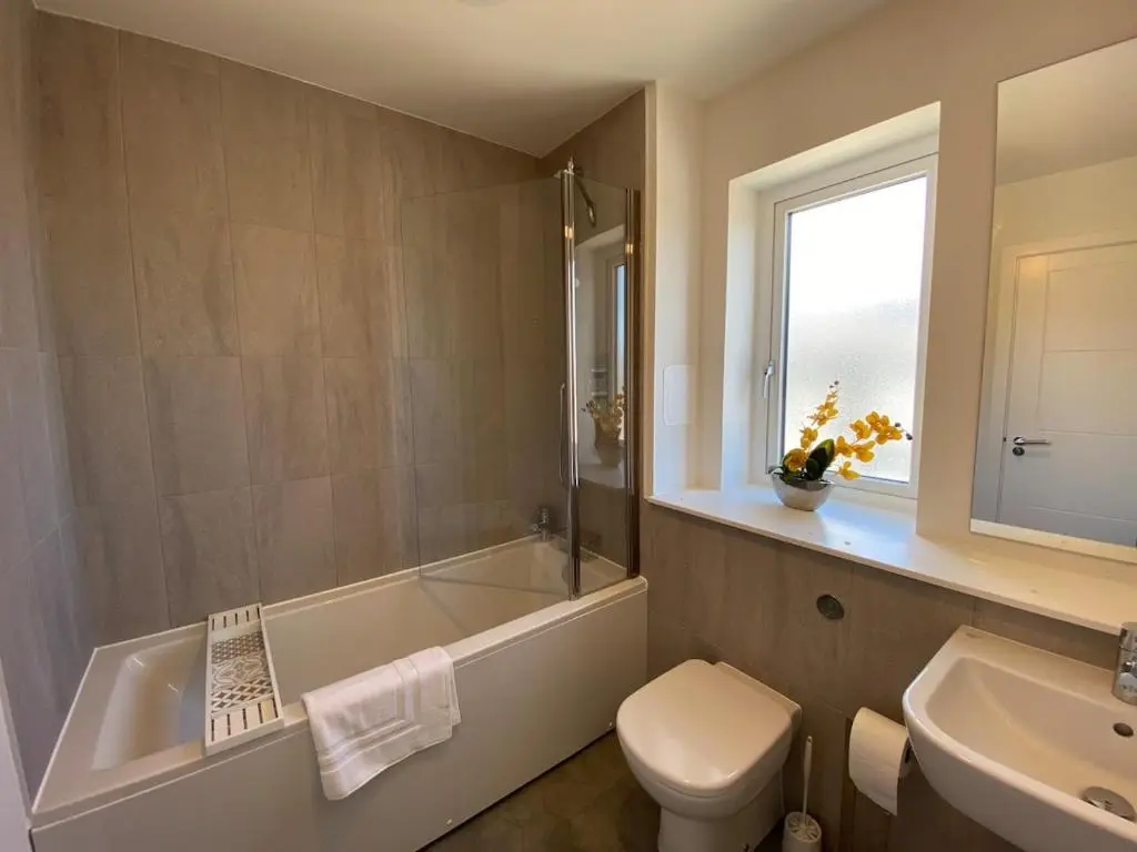 a bathroom with a tub and a toilet and a sink at Modern 4 Bed Highland Home in Culloden