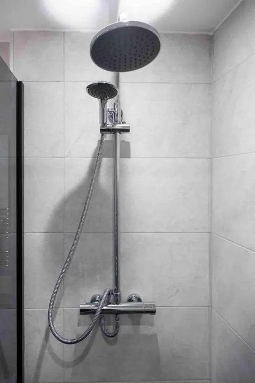 a shower with a shower head in a bathroom at City Centre 3 Bedroom house with parking in Dalneigh