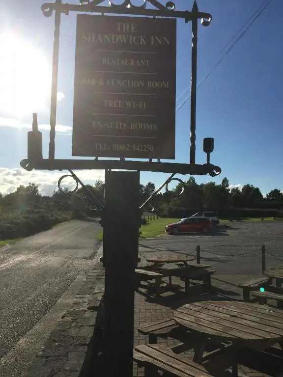 a sign for the shambaughket inn with picnic tables at The Shandwick Inn in Tain