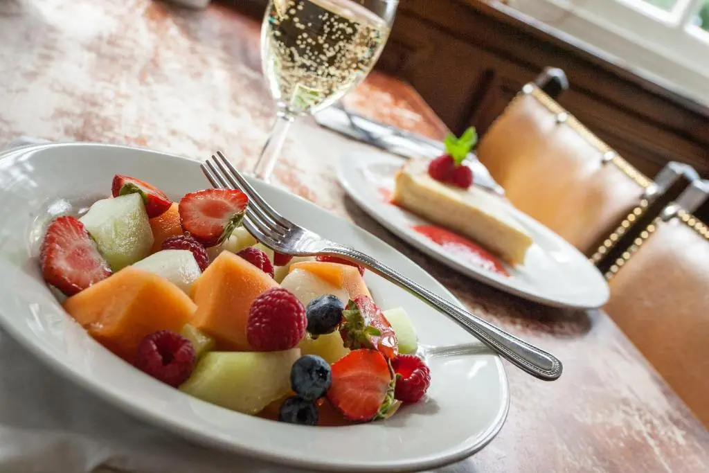 a plate of fruit on a table with a glass of wine at The Shandwick Inn in Tain