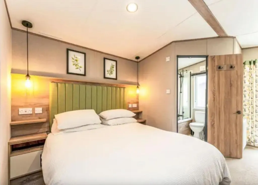 a bedroom with a large white bed and a bathroom at ScottishHighlands in Boat of Garten