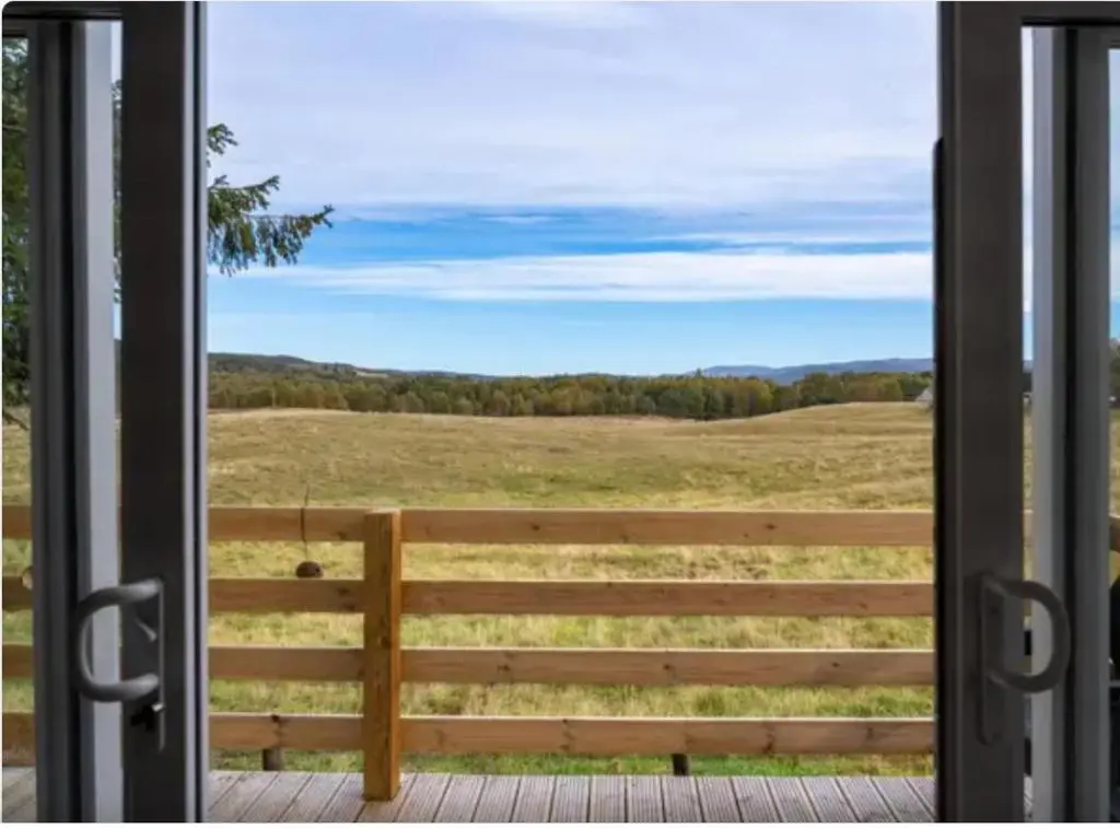 a view of a field from a sliding glass door at ScottishHighlands in Boat of Garten