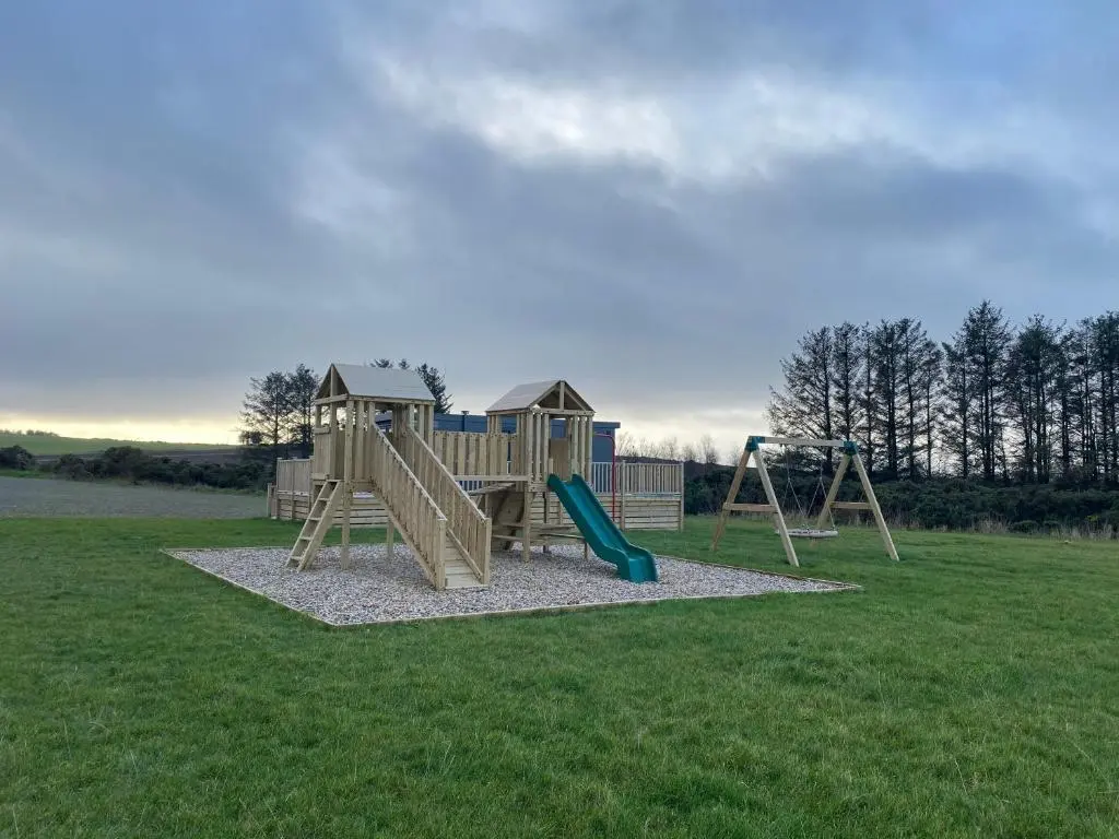a playground with a slide in a field at No 56 Headiton Caravan Park in Banff