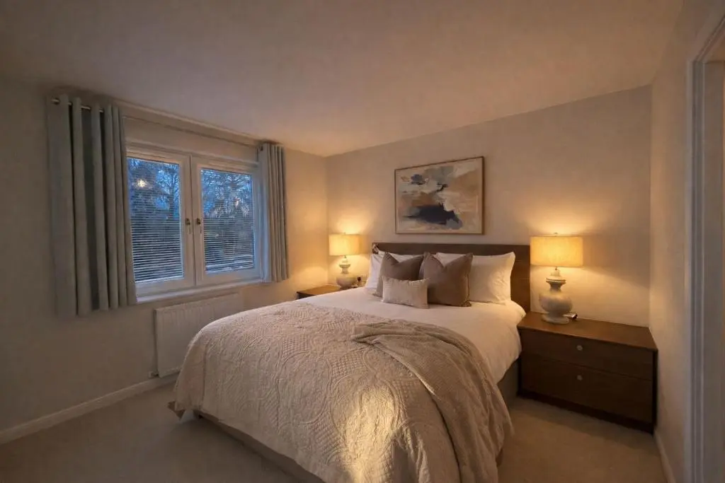 a bedroom with a bed with two lamps and a window at Ness Garden in Inverness
