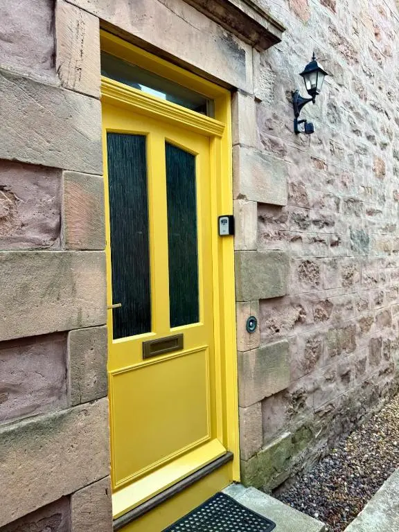 a yellow door on the side of a brick building at The Yellow Door in Inverness