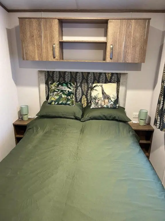a bedroom with a green bed with wooden cabinets at Annas Escape Burnside Moray in Fochabers