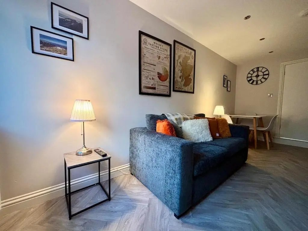 a living room with a blue couch and a table at Cosy cottage in idyllic Speyside setting in Rothes