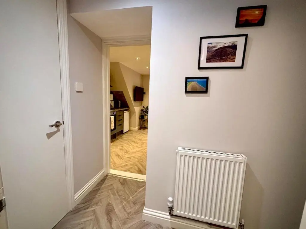 a hallway with a white wall and a radiator at Cosy cottage in idyllic Speyside setting in Rothes