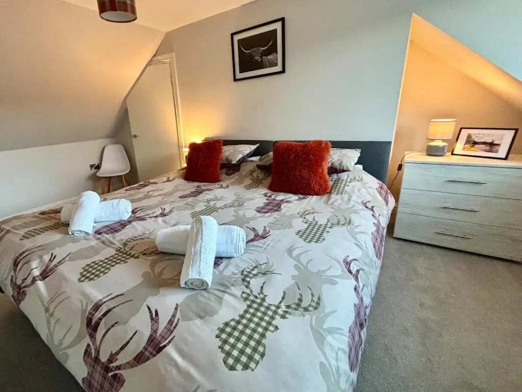 a bedroom with a large bed and a dresser at Cosy cottage in idyllic Speyside setting in Rothes