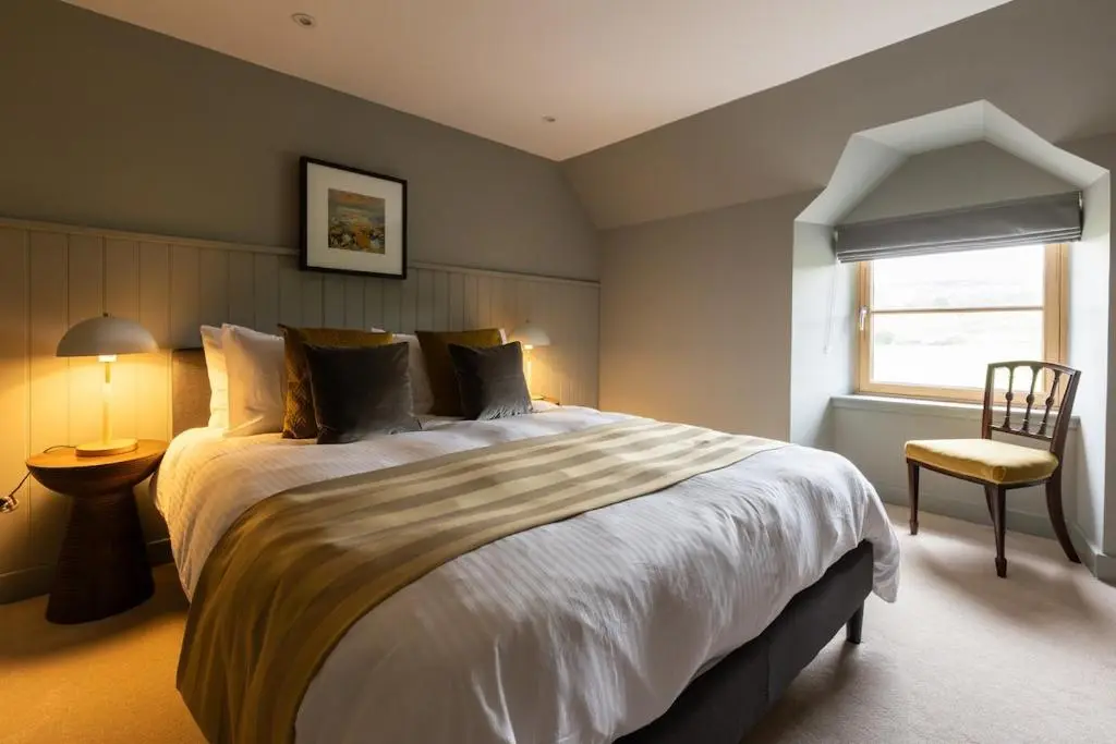a bedroom with a large bed and a chair at Luxury Farmhouse, near Dornoch