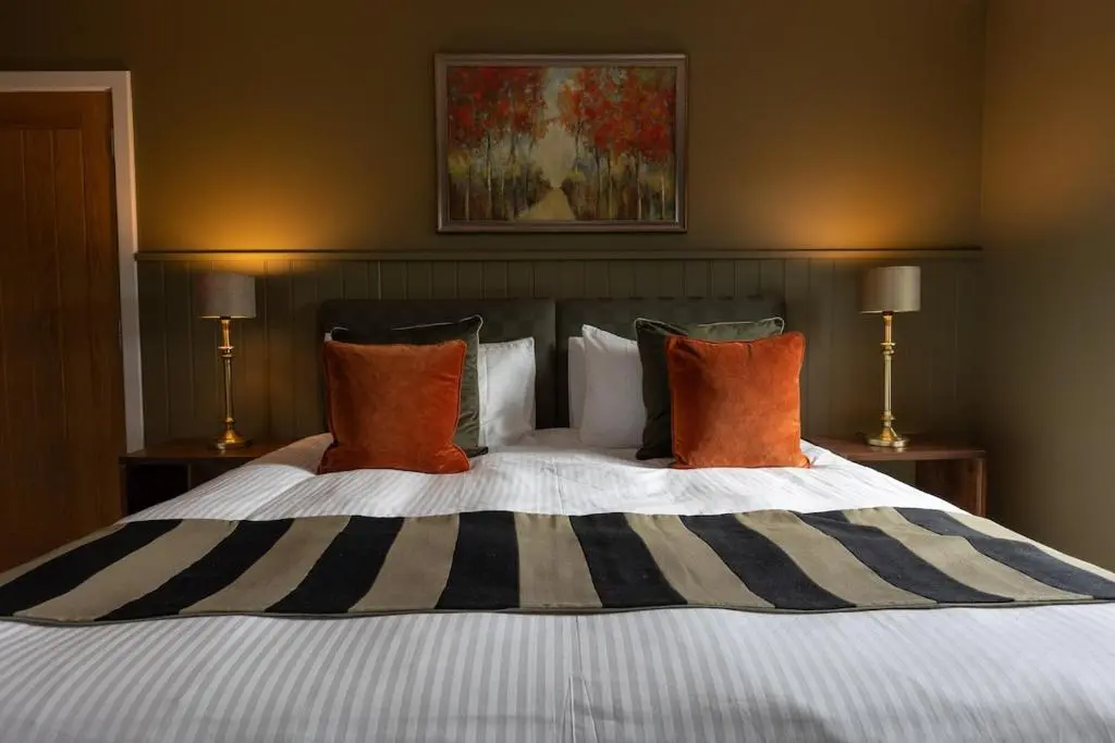 a bedroom with a large bed with orange and black pillows at Luxury Farmhouse, near Dornoch