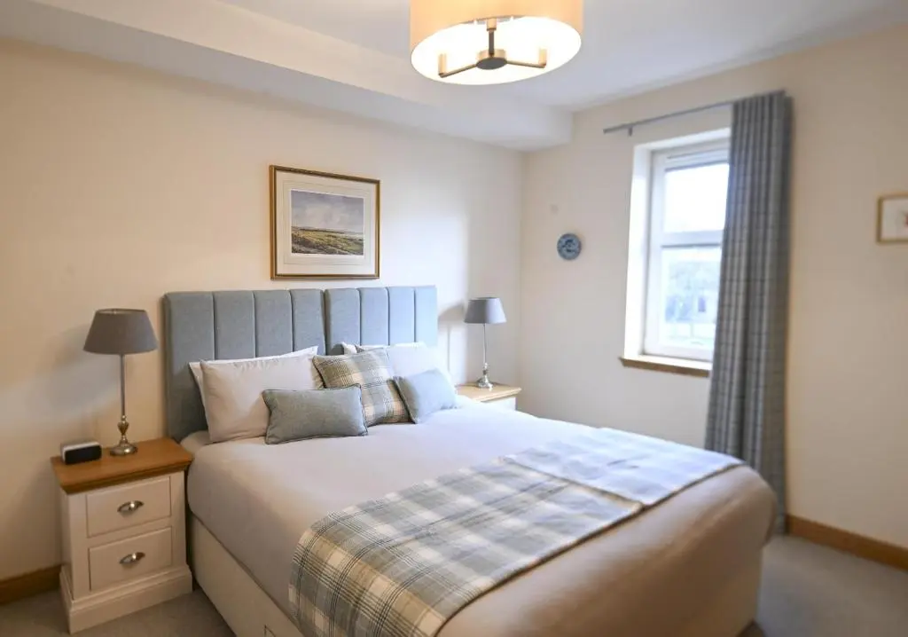 a bedroom with a large bed and a window at Royal Gardens Apartment 5 in Dornoch