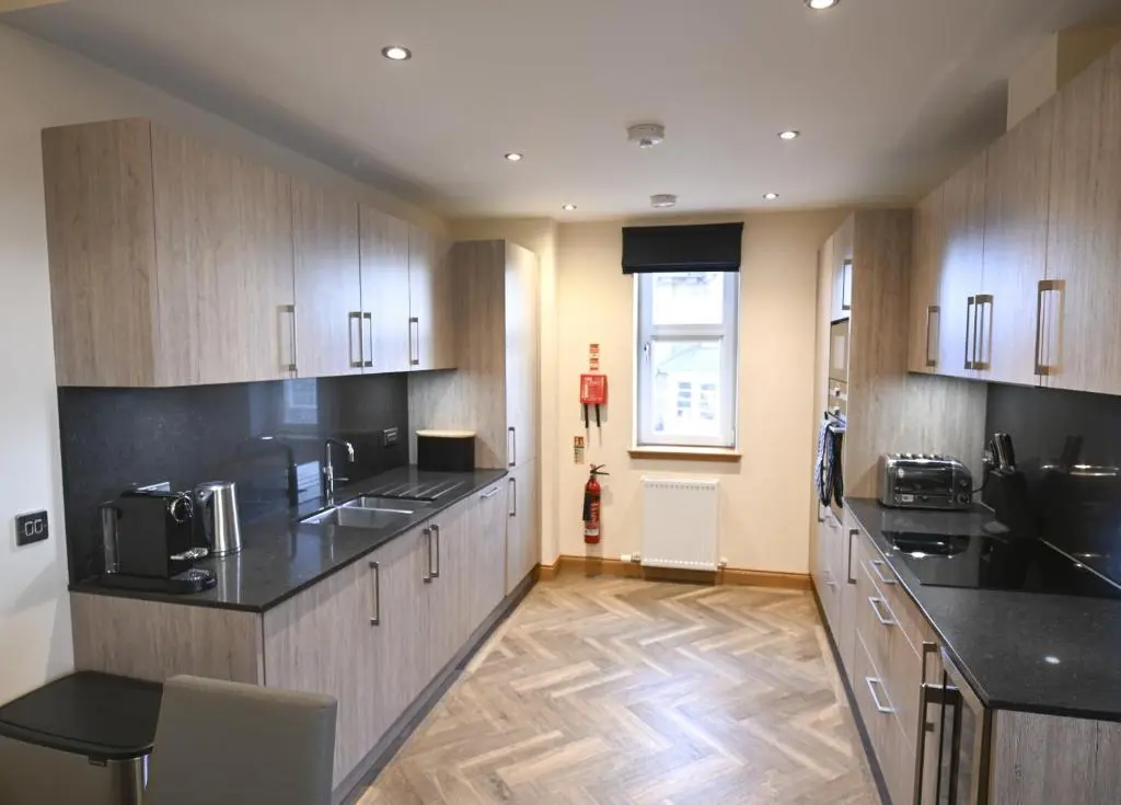 a kitchen with wooden cabinets and black counter tops at Royal Gardens Apartment 5 in Dornoch