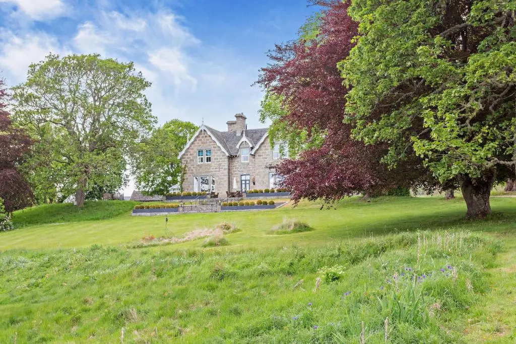an old house in a field with trees and grass at Muckrach Country House in Skye of Curr