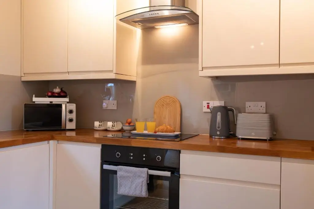 a kitchen with white cabinets and a black oven at Roos Cottage in Ellon
