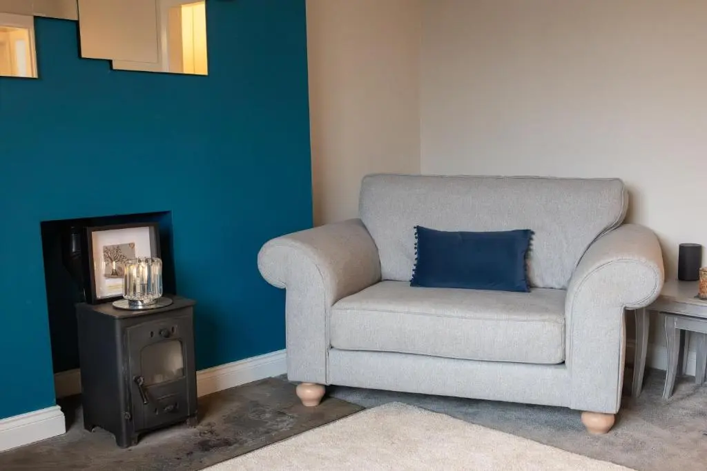 a gray chair with a blue pillow in a room at Roos Cottage in Ellon