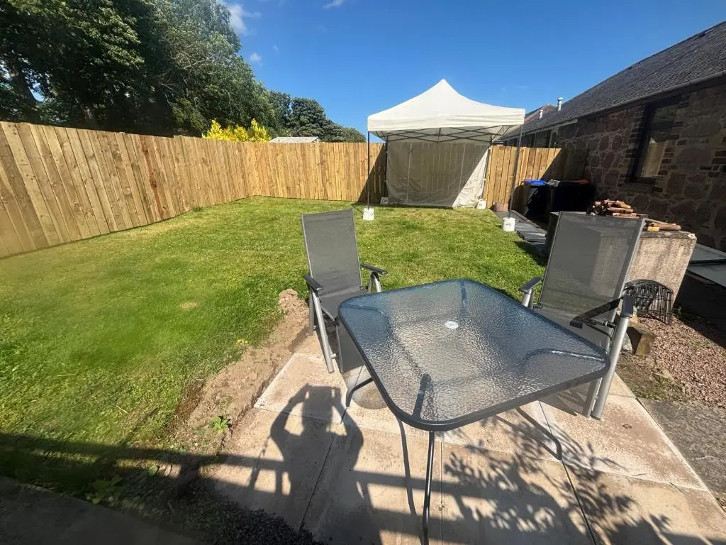 a patio with a table and chairs in a yard at Roos Cottage in Ellon