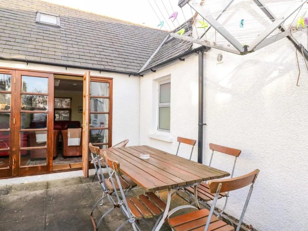 a wooden table and chairs in front of a house at 78 Findhorn in Forres