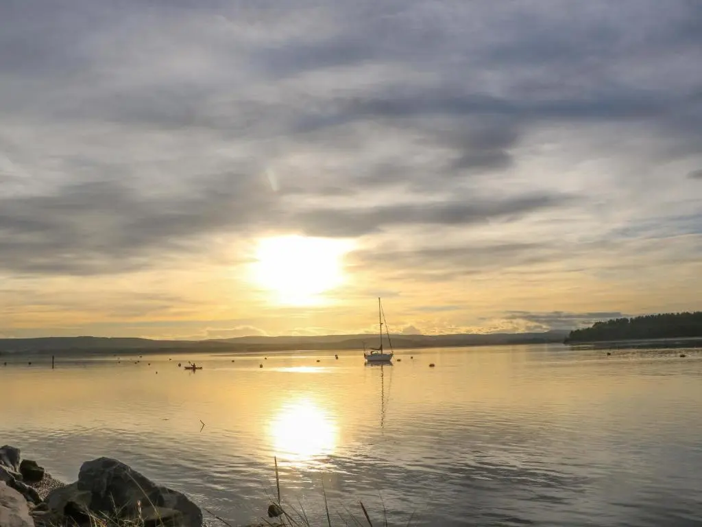 a boat on a lake with the sun in the sky at 78 Findhorn in Forres