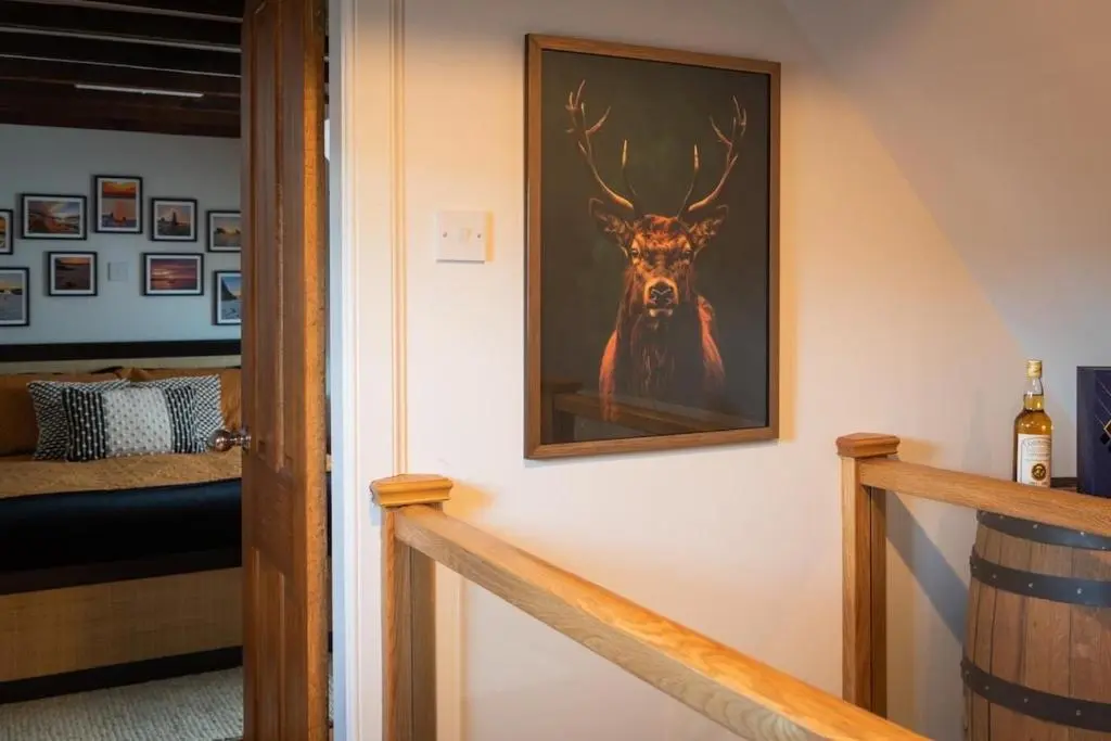 a painting of a deer on a wall next to a staircase at Sea Crest - Beachfront Escape with Whisky Snug in Cullen