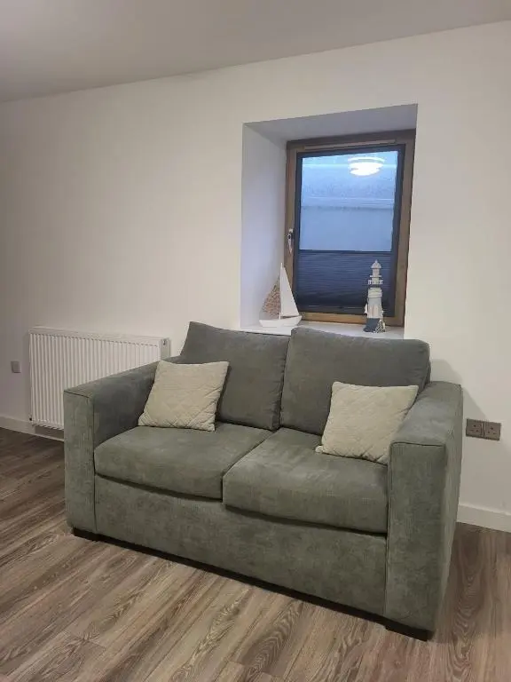 a green couch in a living room with a window at Harbour Nights Lossiemouth in Lossiemouth