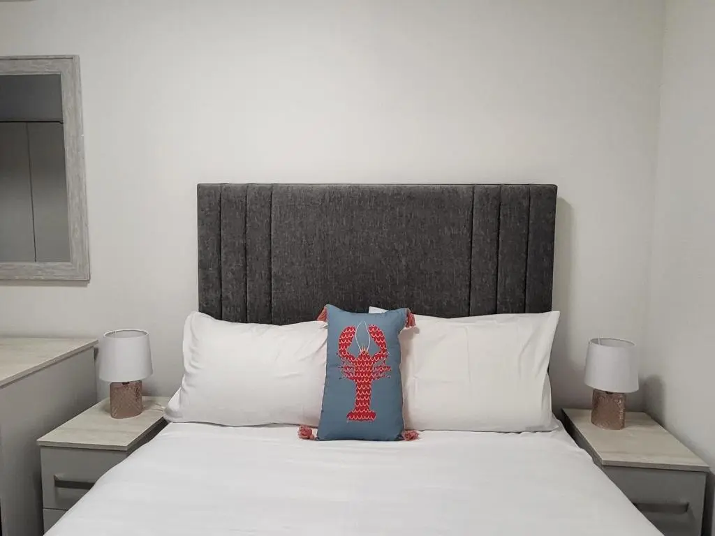 a bedroom with a large bed with white sheets and pillows at Harbour Nights Lossiemouth in Lossiemouth
