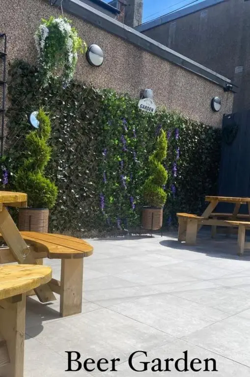a patio with benches and a hedge with purple flowers at TSB Rooms in Turriff