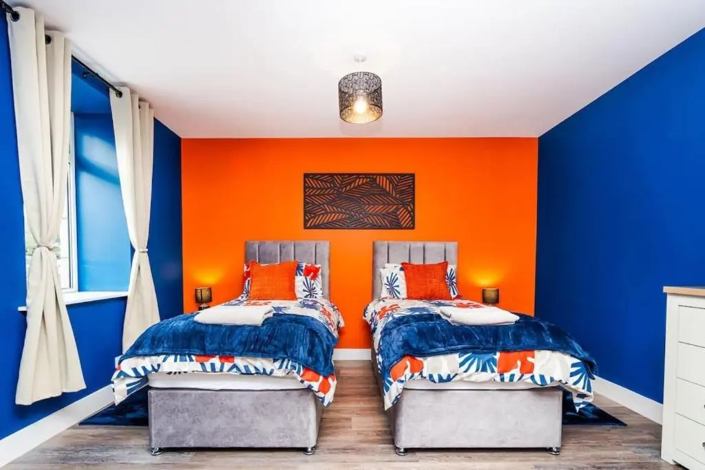 two beds in a room with an orange and blue wall at Airport apartment - Aberdeen - Free Parking in Aberdeen