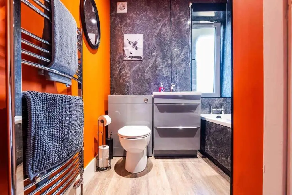 an orange bathroom with a toilet and a sink at Airport apartment - Aberdeen - Free Parking in Aberdeen