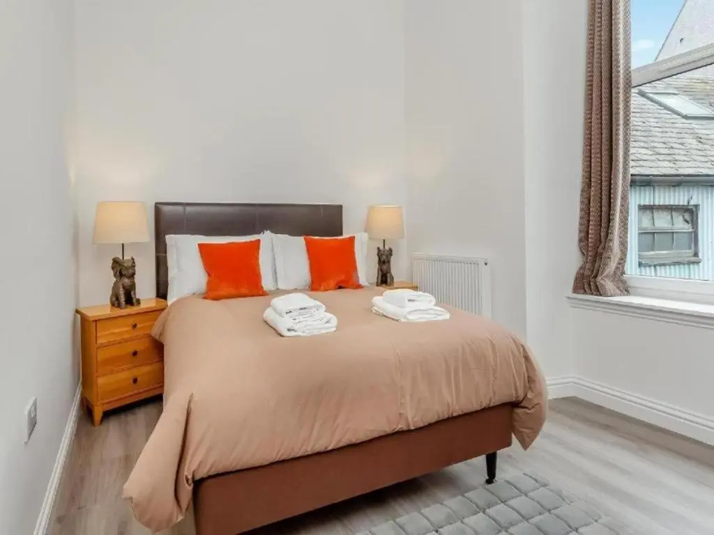 a bedroom with a bed with orange pillows and a window at Family - Parking - Central - Wifi - Sleeps 4 in Inverness