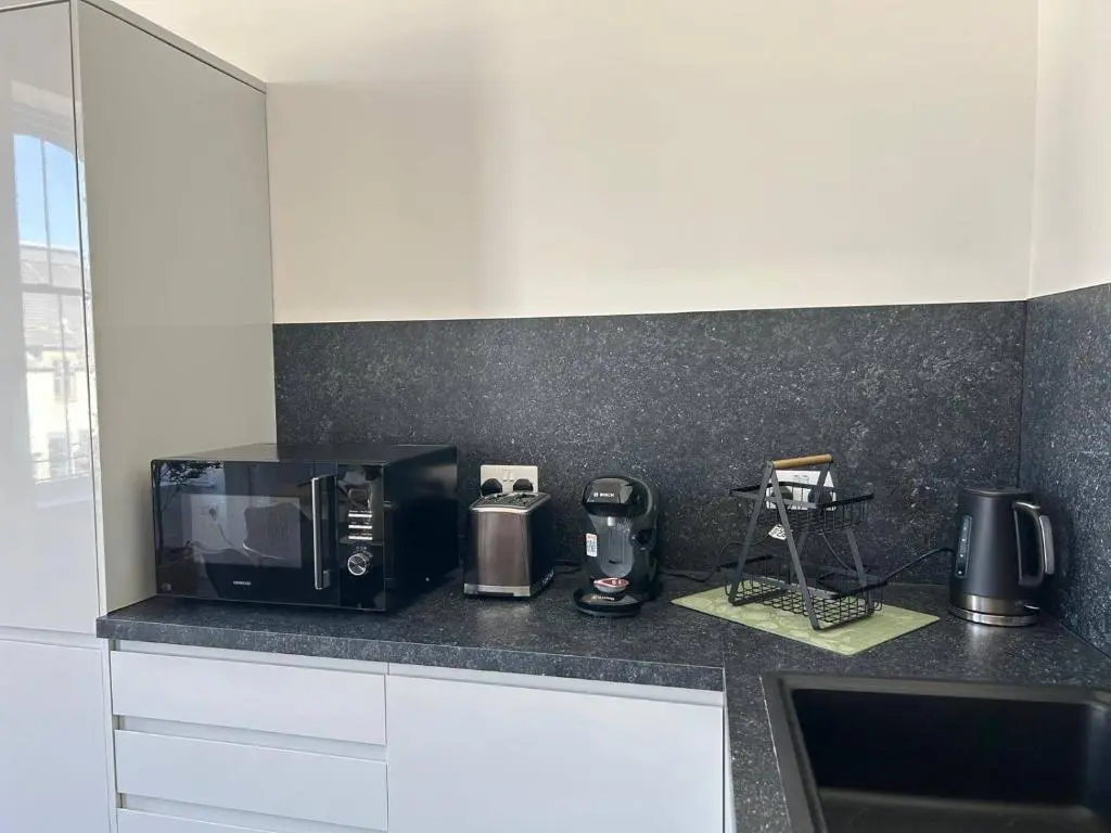 a kitchen with a black counter top with a microwave at Family - Parking - Central - Wifi - Sleeps 4 in Inverness