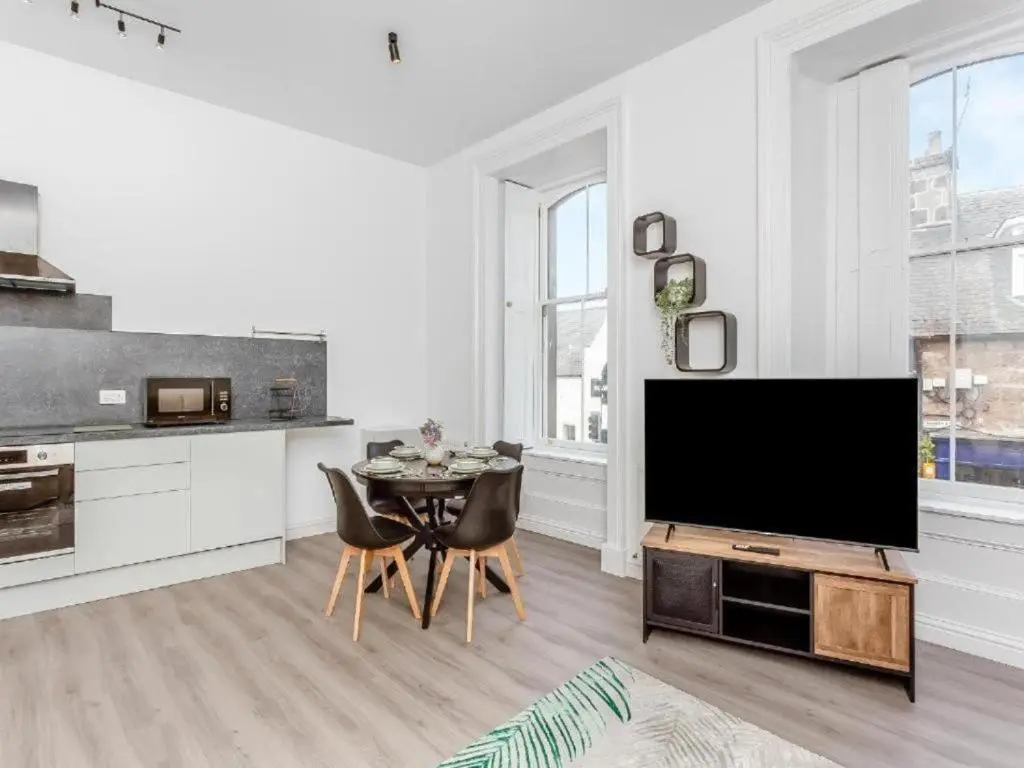 a living room with a television and a table with chairs at Family - Central - Parking - Wifi - Sleeps 4 in Inverness