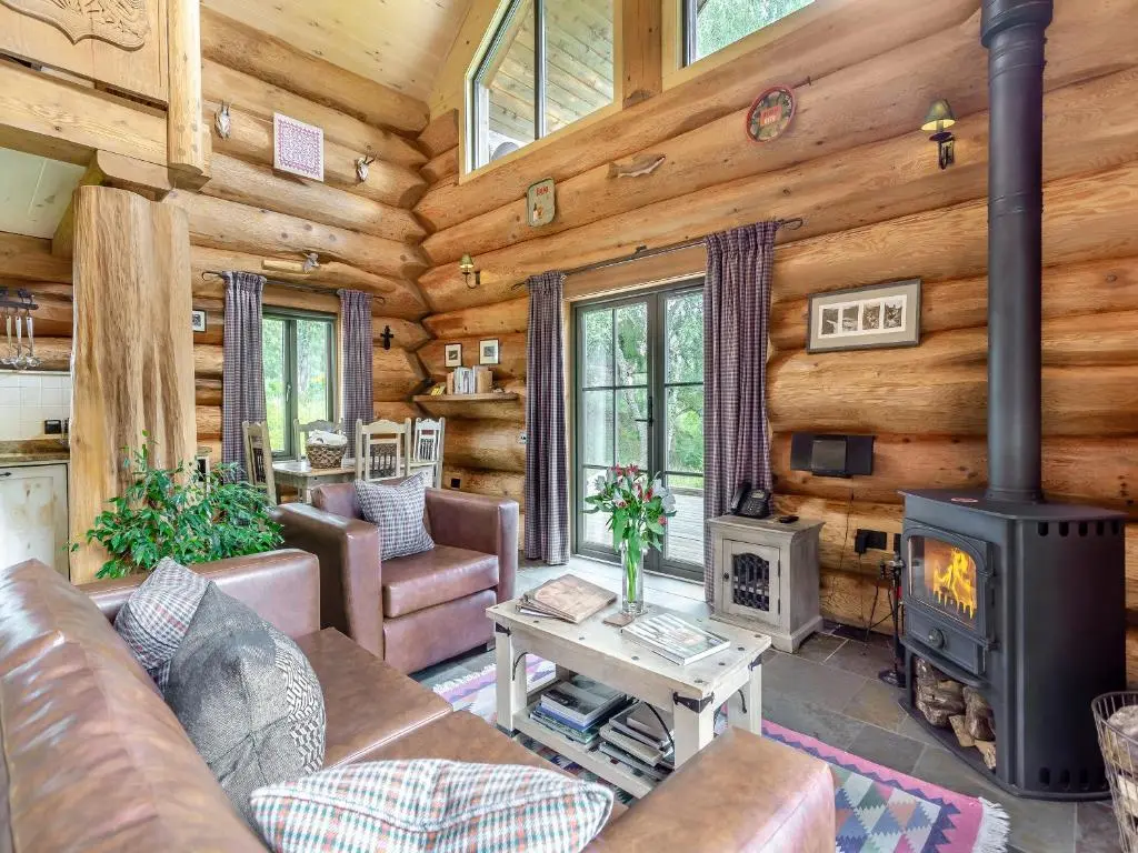a living room with a fireplace in a log cabin at Sylvia - Uk50065 in Struy