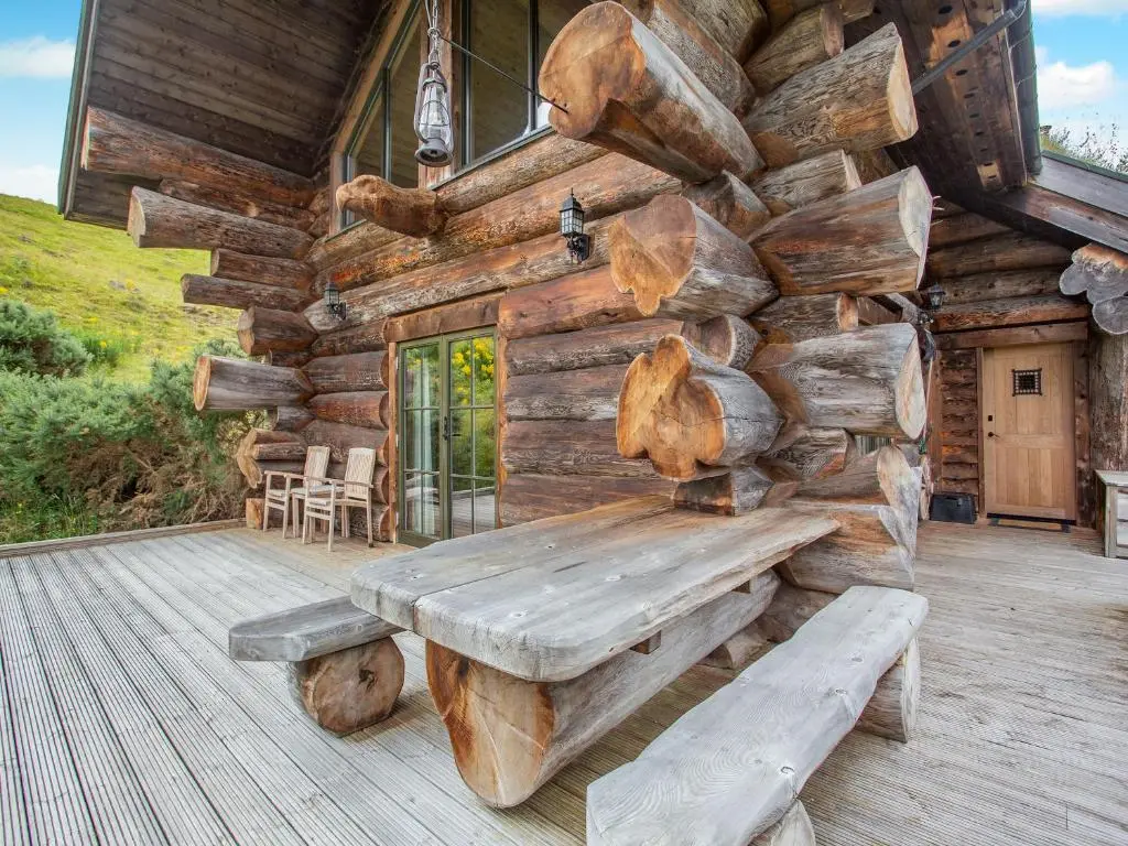 a wooden cabin with a bench on a deck at Strix - Uk50082 in Struy