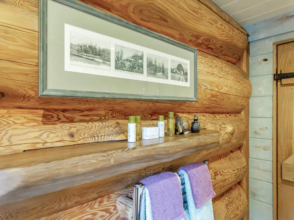 a bathroom with a wooden wall with towels on a shelf at Parus - Uk50083 in Beauly