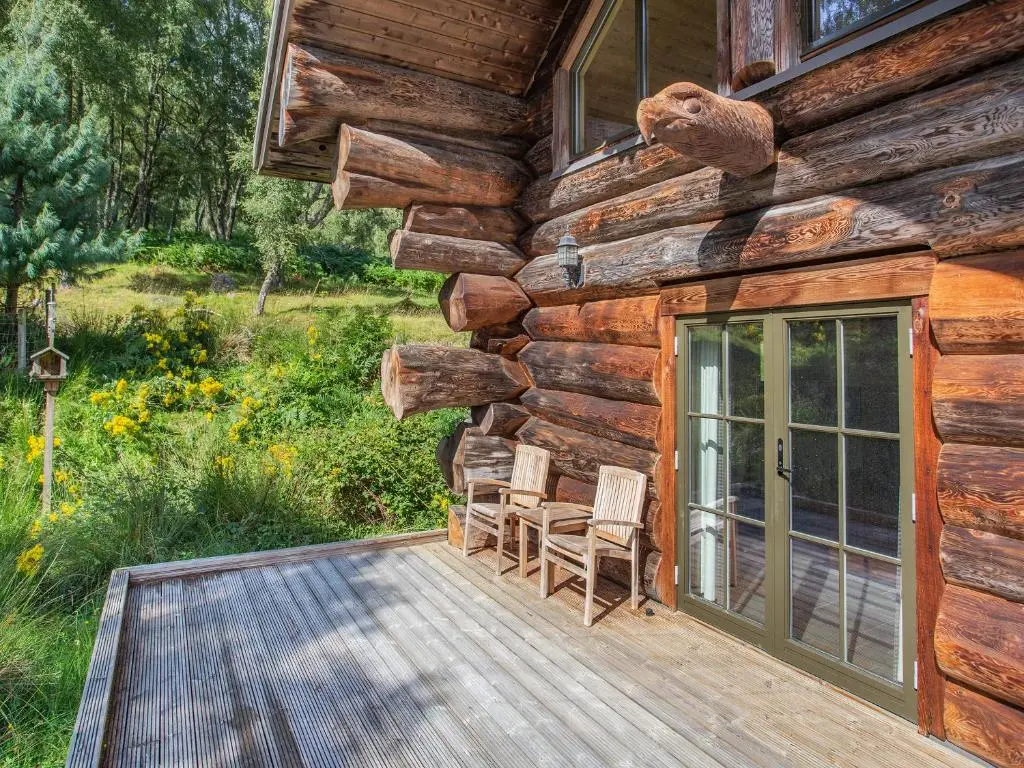 a porch of a log cabin with two chairs at Parus - Uk50083 in Beauly