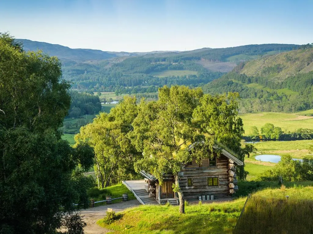 an old cabin in a field with a lake and mountains at Buteo - Uk50068 in Struy