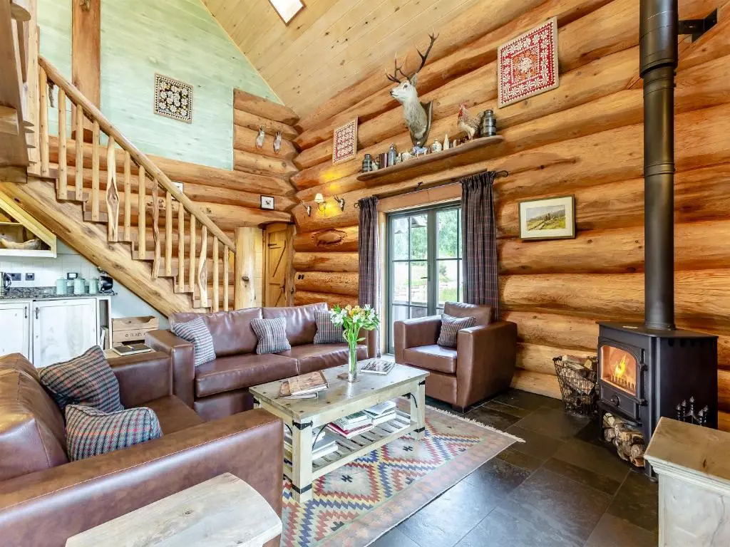 a living room with a couch and a fireplace in a log cabin at Buteo - Uk50068 in Struy