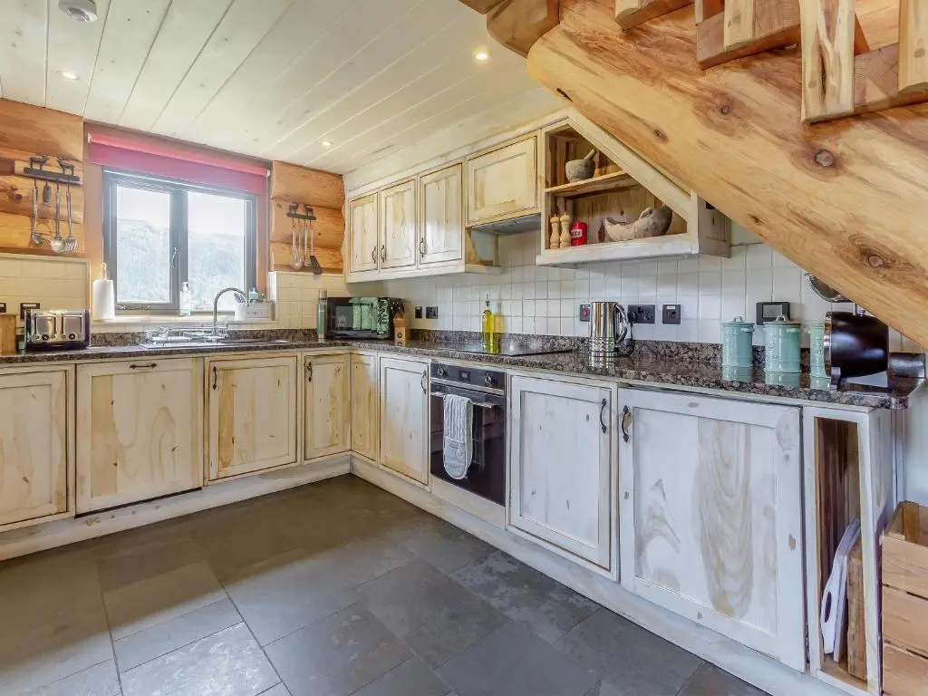 a large kitchen with wooden cabinets and a window at Buteo - Uk50068 in Struy