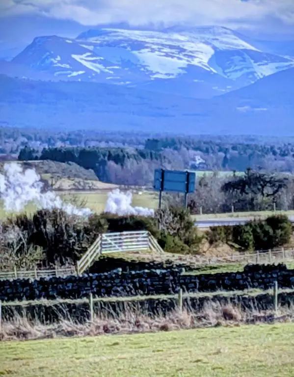 a mountain in the distance with a sign on a hill at Boat 32 in Boat of Garten