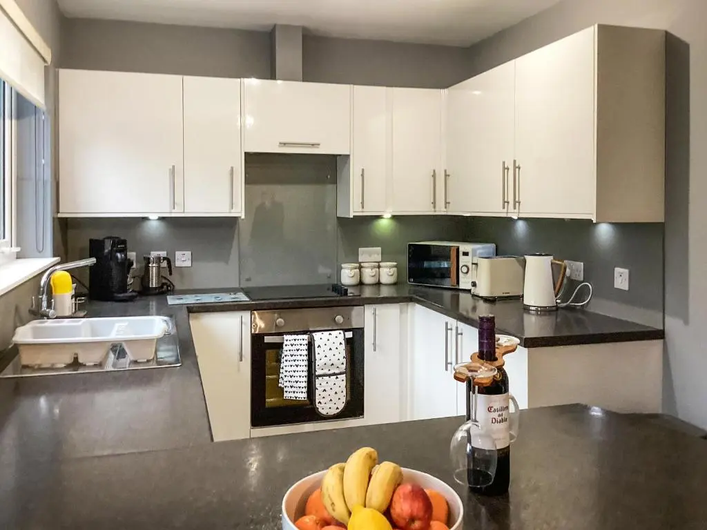 a kitchen with white cabinets and a bowl of fruit on a counter at Uppermill Farm in Tarves
