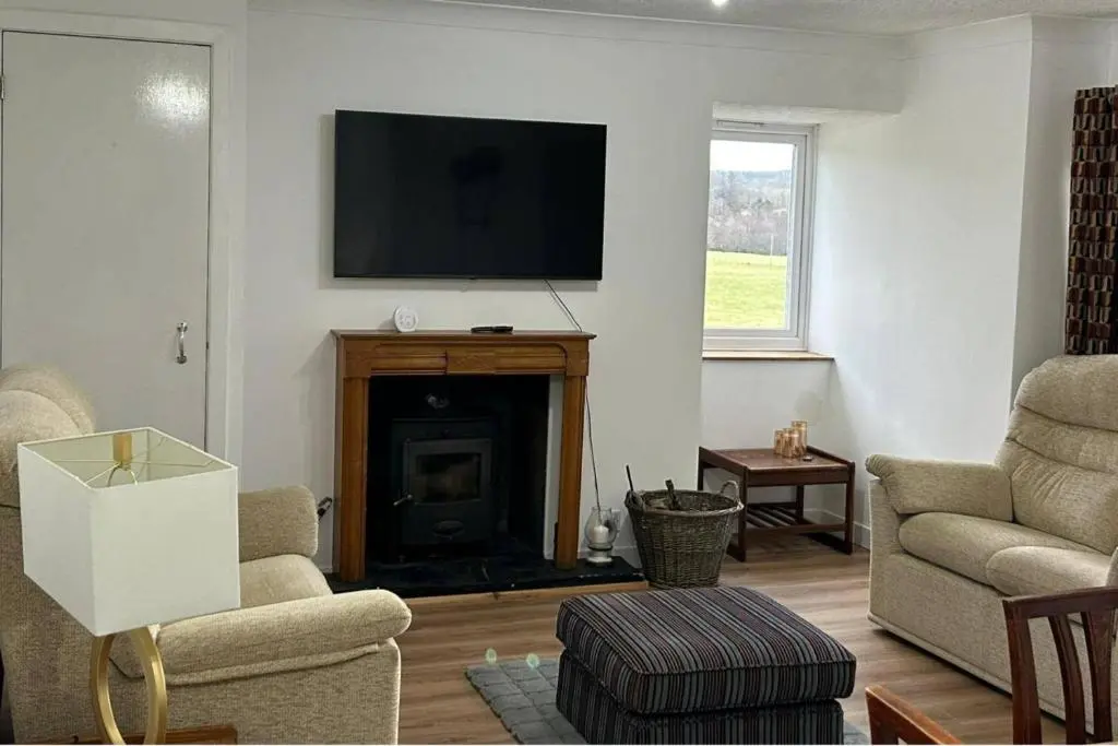 a living room with a fireplace with a flat screen tv at Hot tub - Garden - Bbq - Parking - Pets - Sleeps 6 in Strathpeffer