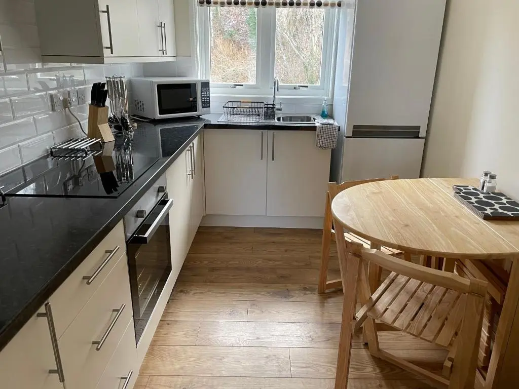 a kitchen with a wooden table and a counter top at Millburn Court Apartment in Inverness