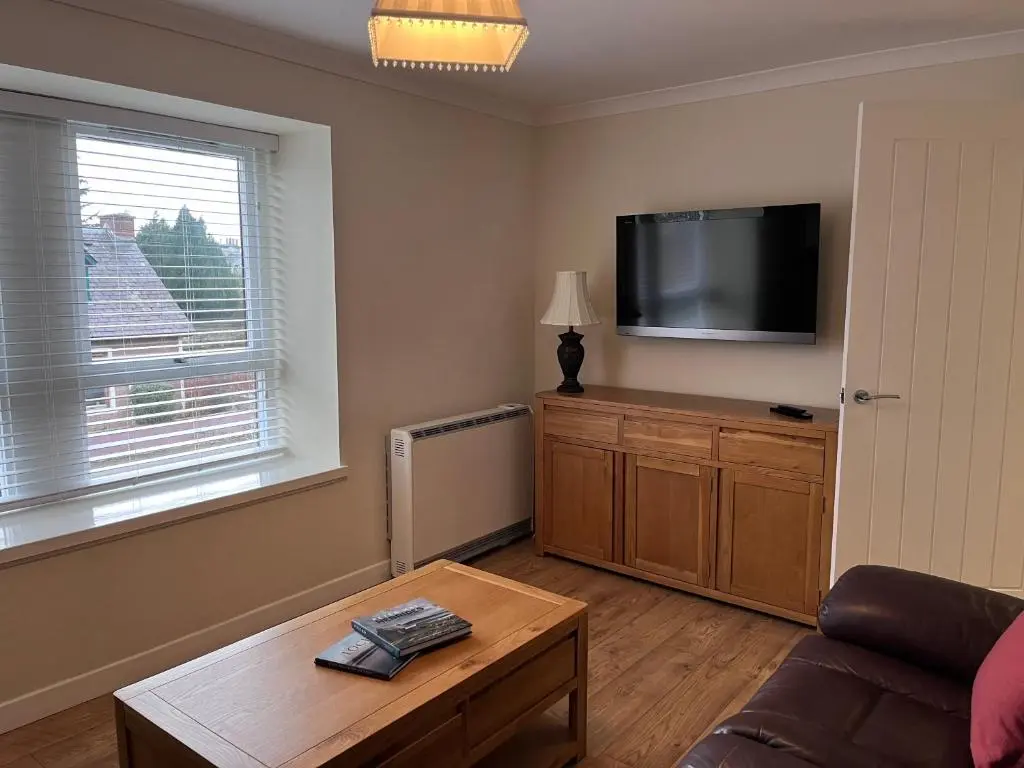 a living room with a couch and a flat screen tv at Millburn Court Apartment in Inverness
