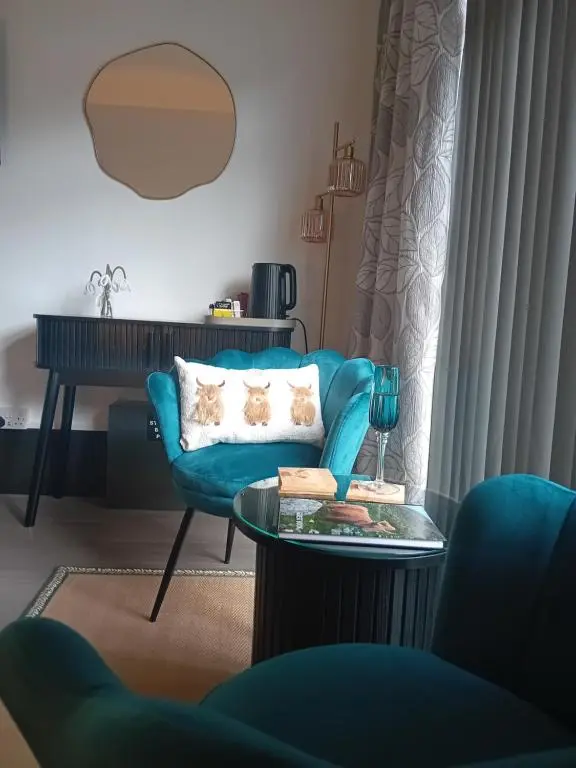 a living room with a blue couch and a table at The Snug on The Brae in Inshes