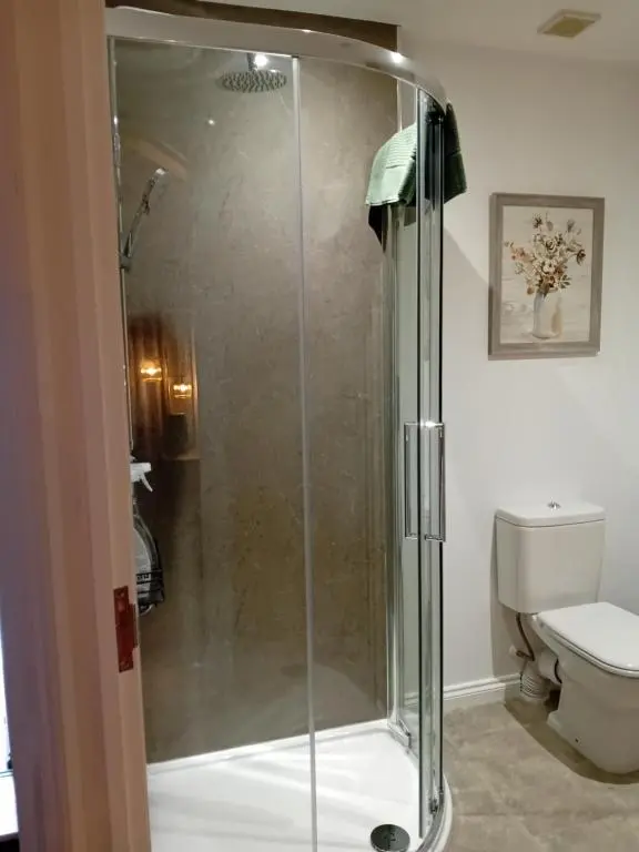 a glass shower in a bathroom with a toilet at The Snug on The Brae in Inshes