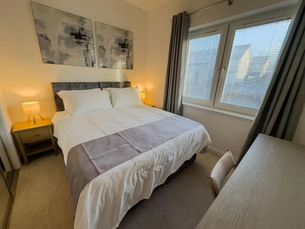 a bedroom with a large bed and two windows at Beinn View in Inverness