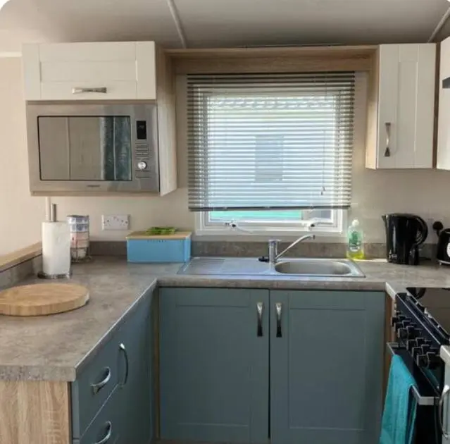 a kitchen with blue cabinets and a sink and a window at Moray Coast getaway in Lossiemouth
