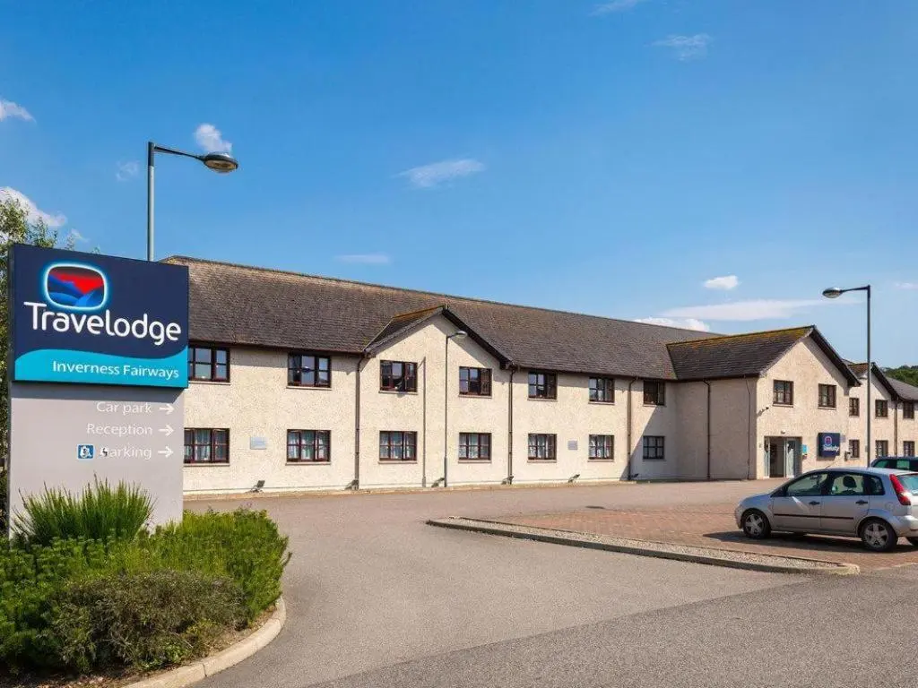 a large building with a car parked in a parking lot at Travelodge Inverness Fairways in Inshes