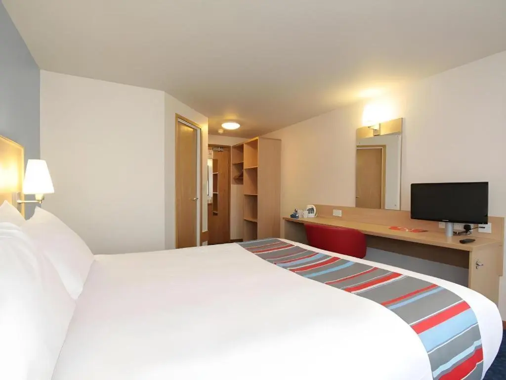 a hotel room with a white bed and a desk at Travelodge Inverness Fairways in Inshes